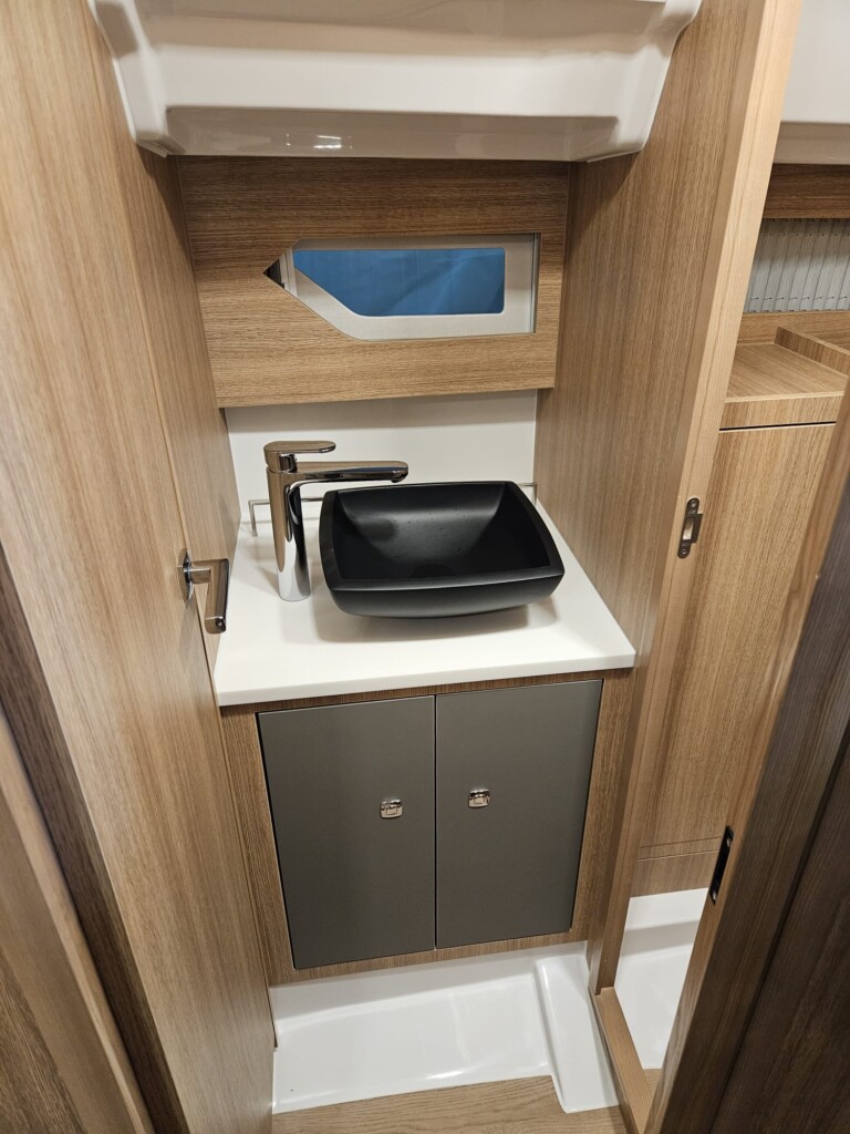 The bathroom is through. One side leads to the starboard aft cabin, and the other side has a door where the shower stall with toilet is located